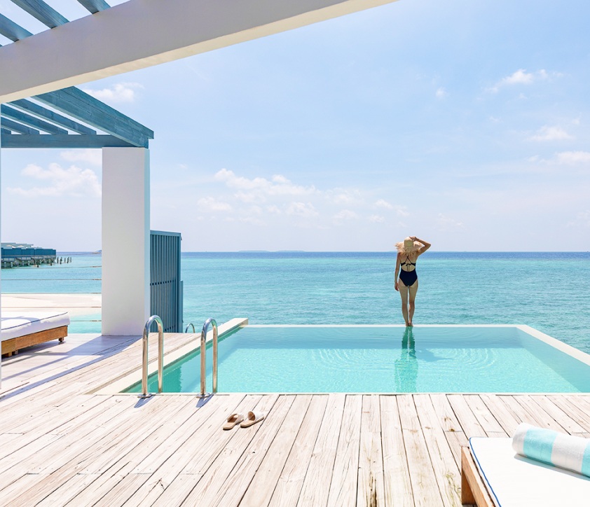 A woman standing alongside the freshwater pool and enjoying the ocean view from our Maldives Lagoon Villa.