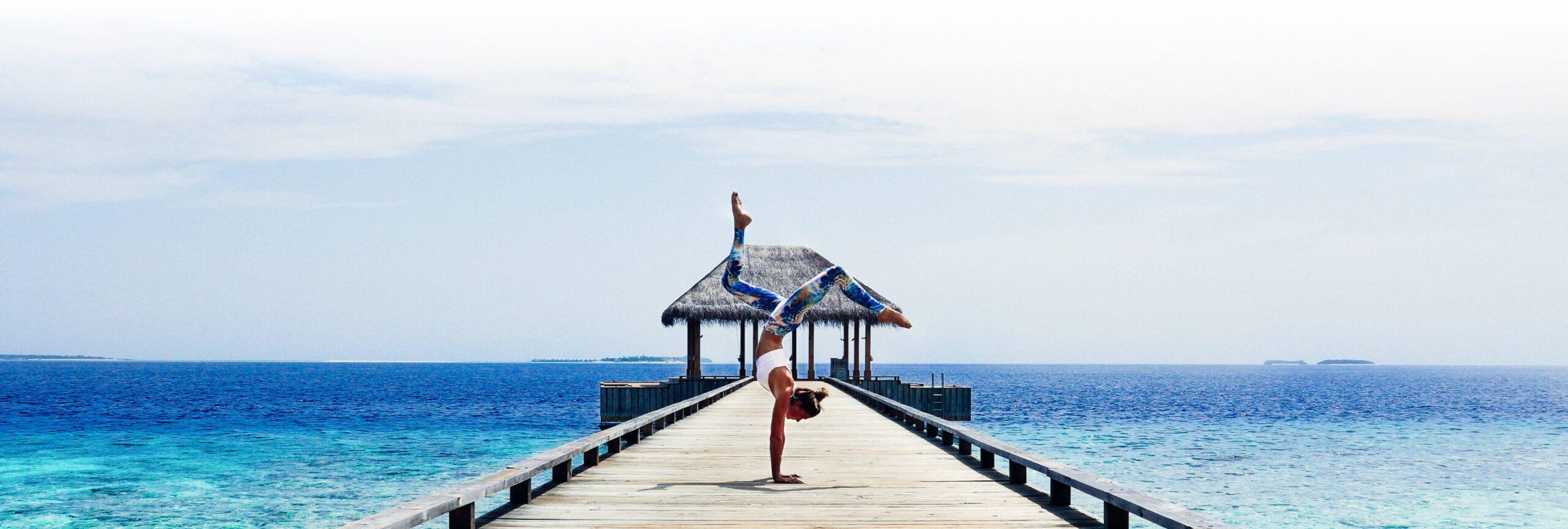 A visiting practitioner practicing yoga on a pier, part of Amilla Maldives' wellbeing programmes