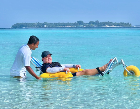 A guest at Amilla Maldives using one of our beach wheelchairs to enjoy the water.