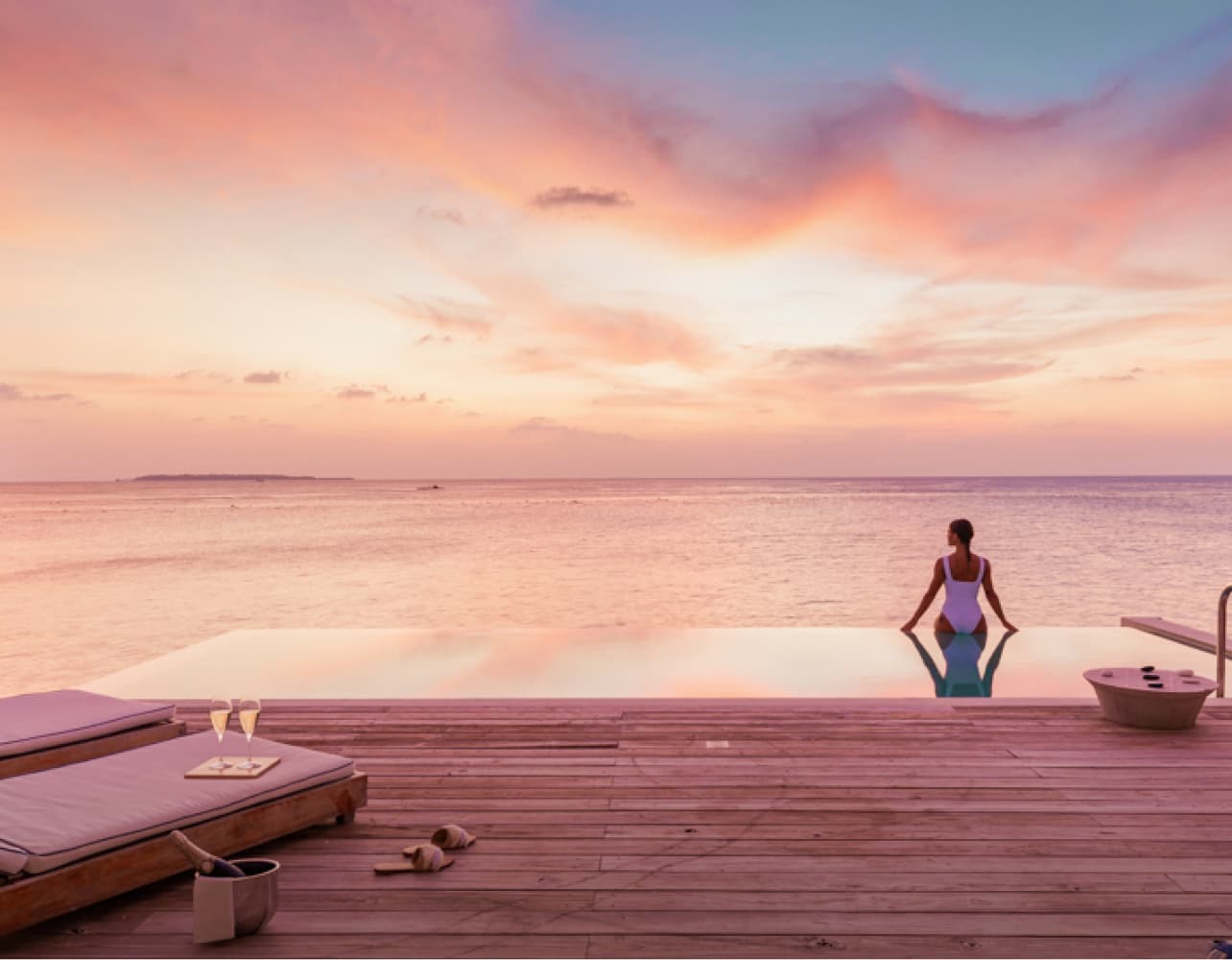 A woman relaxing and enjoying the ocean view from the freshwater pool at our Sunset Water Villa Maldives.