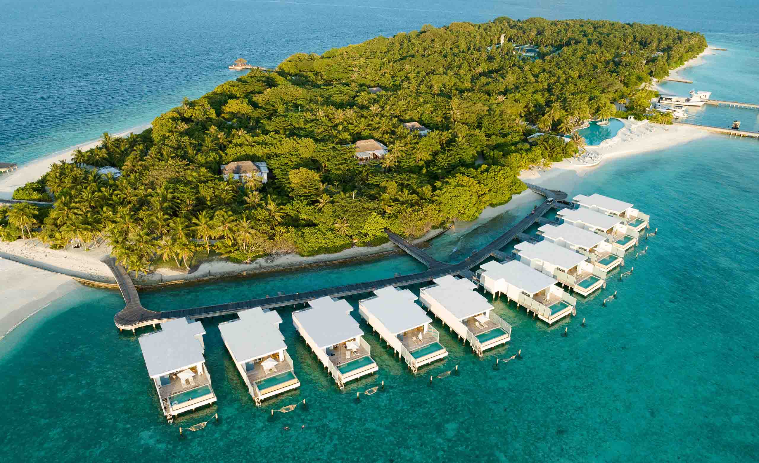 An overhead view of our Sunset Water Villas with private pool and hammocks situated over the ocean.